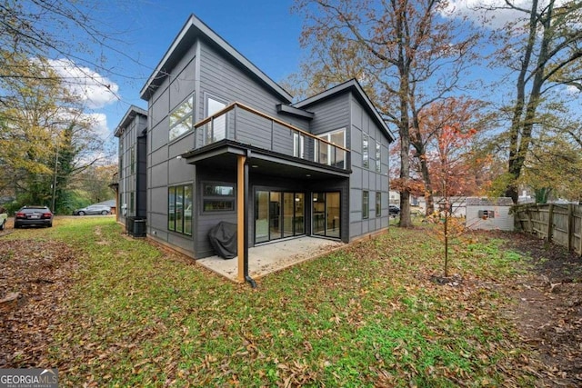 rear view of property featuring a lawn, a balcony, and a patio area