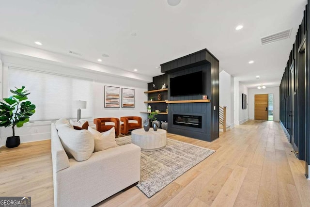 living room with a large fireplace and light wood-type flooring