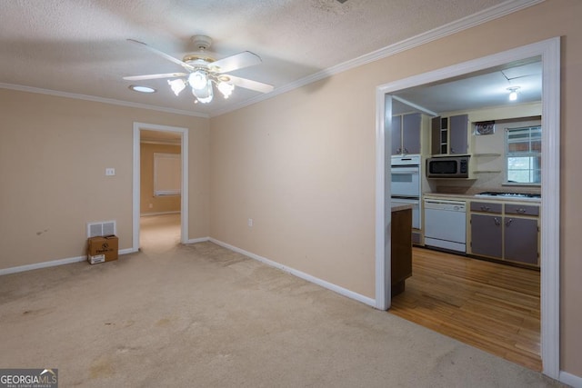 kitchen with carpet, white appliances, crown molding, and a textured ceiling