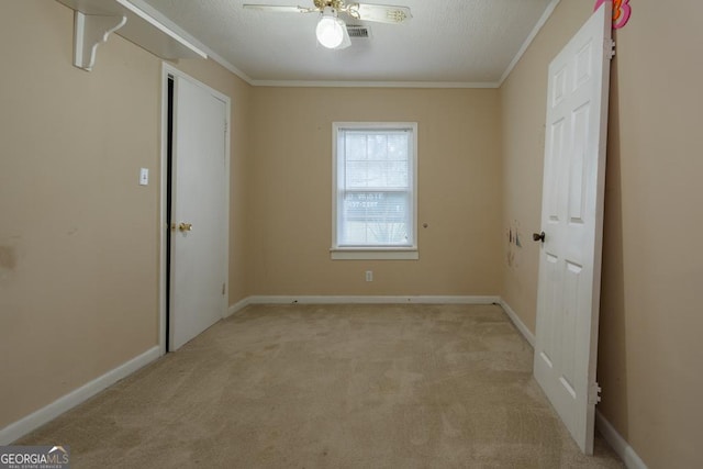 carpeted empty room with crown molding, ceiling fan, and a textured ceiling