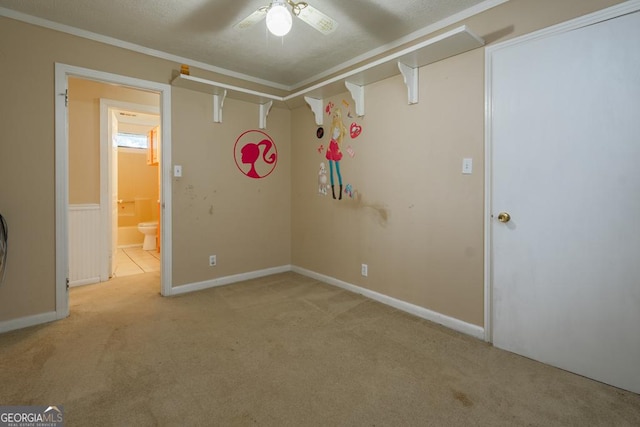 carpeted spare room with ceiling fan, a textured ceiling, and ornamental molding