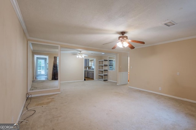 empty room featuring a textured ceiling, light colored carpet, ceiling fan, and crown molding