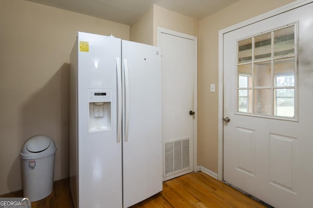 kitchen featuring wood-type flooring and white fridge with ice dispenser