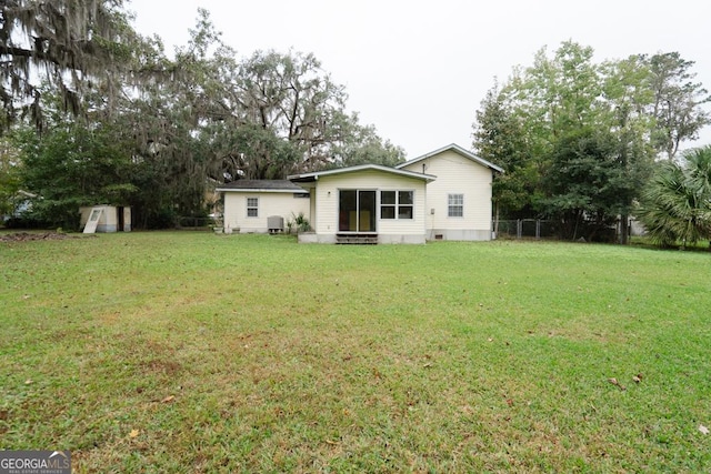 back of house with central AC, a yard, and a shed