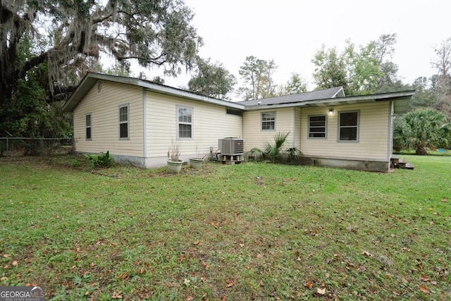 rear view of property featuring a yard and central air condition unit