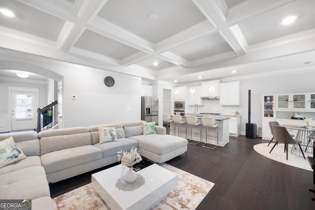 living room with beam ceiling, crown molding, sink, and dark hardwood / wood-style floors