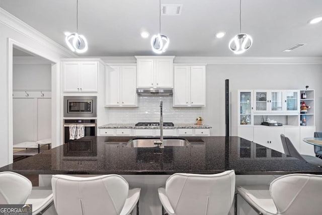 kitchen with pendant lighting, white cabinets, stainless steel appliances, and dark stone counters