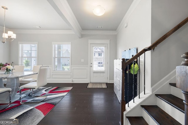 foyer entrance with ornamental molding, plenty of natural light, dark wood-type flooring, and a notable chandelier