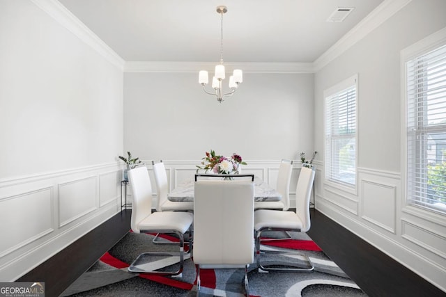 dining space featuring ornamental molding, a wealth of natural light, and an inviting chandelier