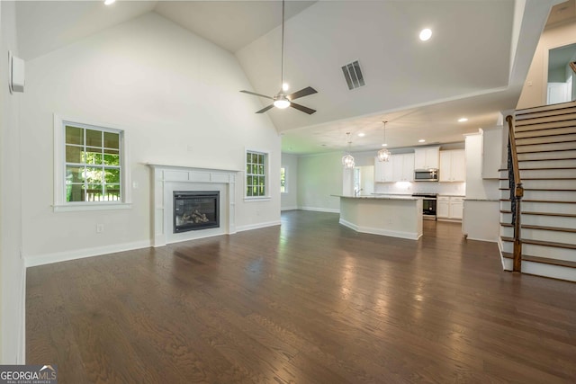 unfurnished living room with ceiling fan, dark wood-type flooring, and high vaulted ceiling