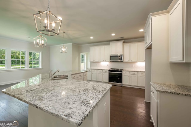 kitchen featuring white cabinets, appliances with stainless steel finishes, hanging light fixtures, and dark wood-type flooring