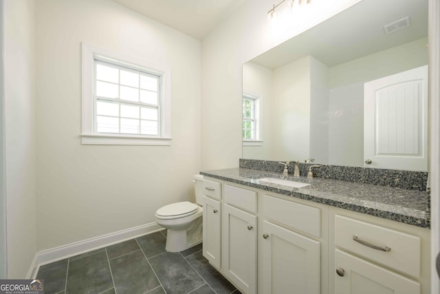 bathroom featuring tile patterned flooring, vanity, toilet, and a healthy amount of sunlight