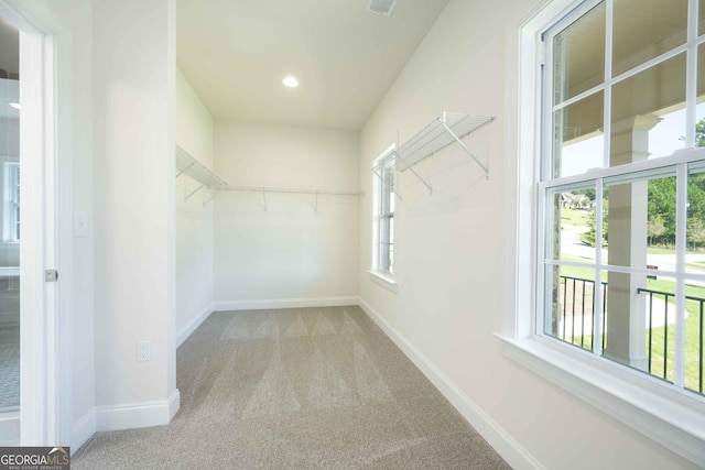 spacious closet with light colored carpet and vaulted ceiling