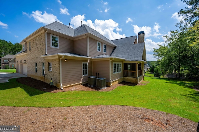 rear view of property with a yard, a garage, and cooling unit