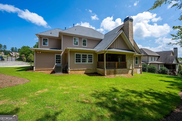 rear view of property with central AC unit and a lawn