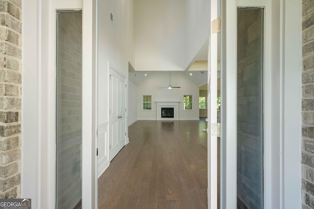 corridor with high vaulted ceiling and dark wood-type flooring