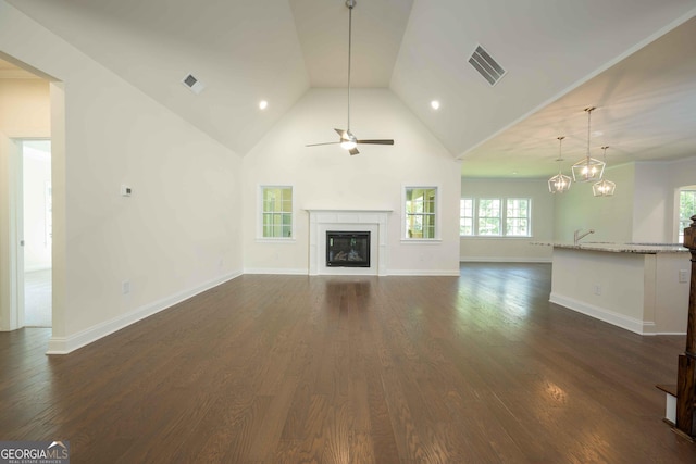 unfurnished living room with ceiling fan with notable chandelier, dark hardwood / wood-style flooring, and high vaulted ceiling