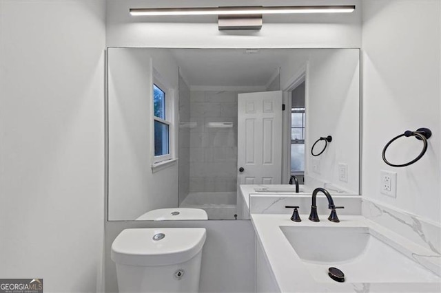 bathroom featuring a tile shower, vanity, and toilet