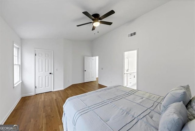 bedroom with vaulted ceiling, ensuite bathroom, ceiling fan, and wood-type flooring