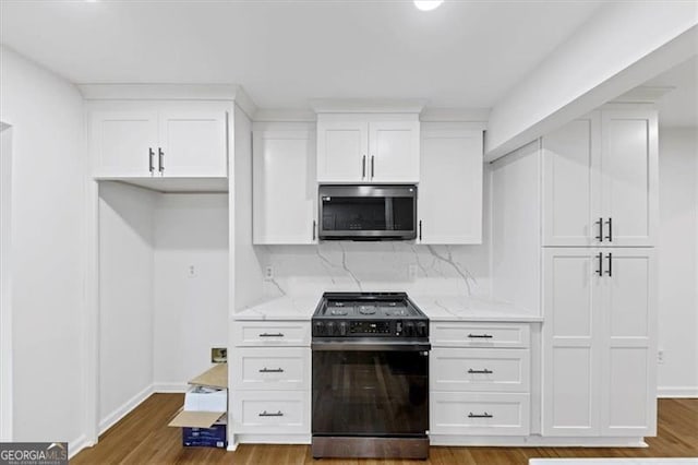 kitchen featuring hardwood / wood-style floors, light stone counters, white cabinetry, stove, and tasteful backsplash