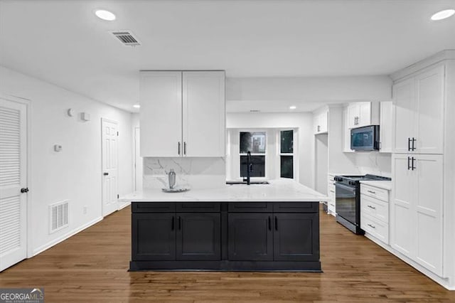 kitchen featuring dark hardwood / wood-style flooring, range with gas cooktop, tasteful backsplash, and white cabinetry