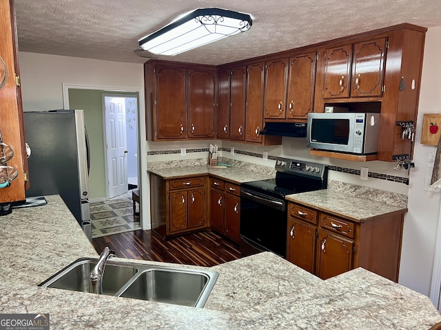 kitchen with sink, dark hardwood / wood-style floors, a textured ceiling, and appliances with stainless steel finishes