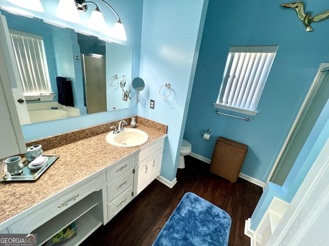 bathroom with vanity, hardwood / wood-style flooring, toilet, and a shower with shower door