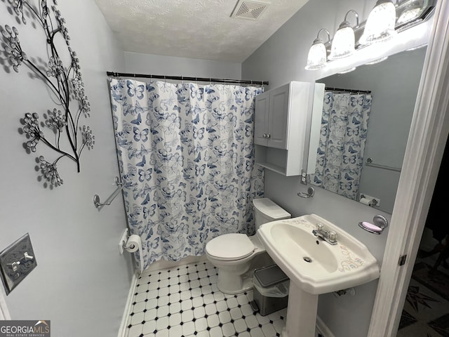 bathroom featuring tile patterned floors, a textured ceiling, toilet, and curtained shower