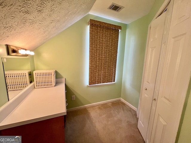 interior space with lofted ceiling, a closet, carpet floors, and a textured ceiling