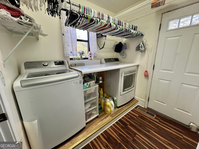 clothes washing area with separate washer and dryer and dark hardwood / wood-style flooring