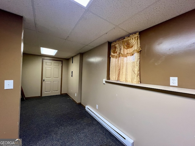 hallway featuring a drop ceiling, dark carpet, and a baseboard radiator