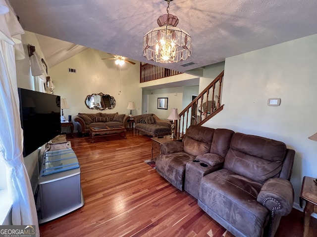 living room with wood-type flooring, ceiling fan with notable chandelier, a textured ceiling, and vaulted ceiling