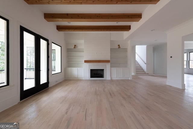 unfurnished living room with beamed ceiling, light hardwood / wood-style flooring, a fireplace, and built in shelves