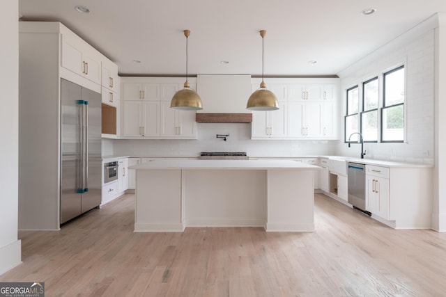 kitchen featuring a center island, appliances with stainless steel finishes, custom range hood, light hardwood / wood-style floors, and white cabinets