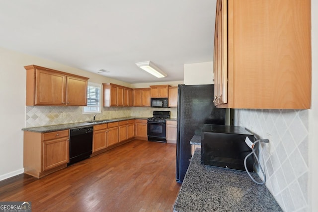 kitchen with dark stone countertops, sink, black appliances, and dark hardwood / wood-style floors