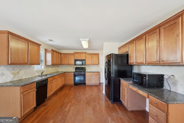 kitchen featuring sink, tasteful backsplash, hardwood / wood-style floors, dark stone counters, and black appliances