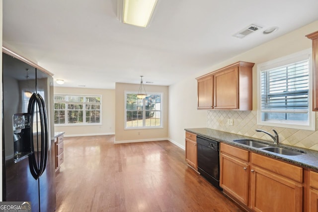 kitchen with stainless steel refrigerator with ice dispenser, tasteful backsplash, sink, black dishwasher, and plenty of natural light