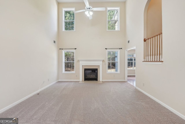 unfurnished living room with light carpet, a towering ceiling, and a wealth of natural light