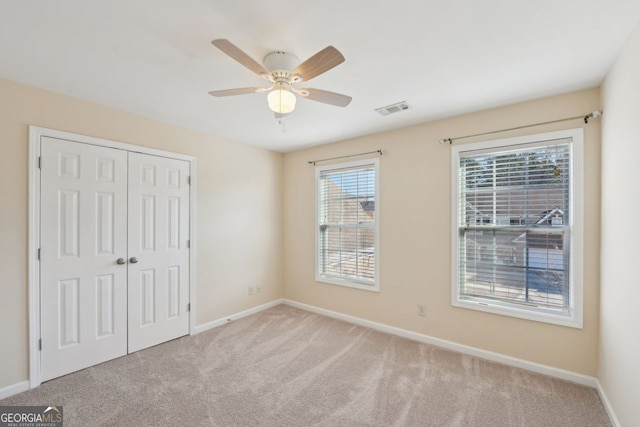 unfurnished bedroom featuring ceiling fan, a closet, and light carpet