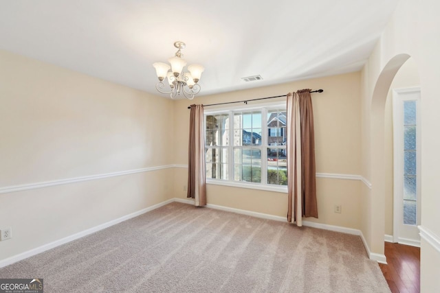 empty room featuring carpet floors and an inviting chandelier