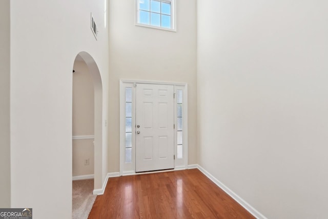 foyer entrance with wood-type flooring and a high ceiling