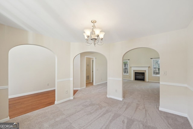 carpeted empty room featuring a chandelier