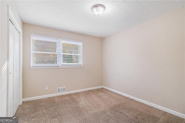 unfurnished room featuring carpet and a textured ceiling