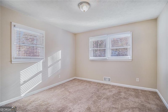 carpeted empty room featuring a textured ceiling