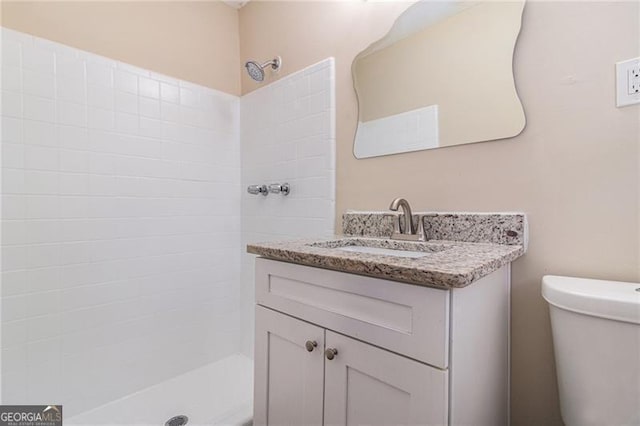 bathroom with vanity, toilet, and a tile shower