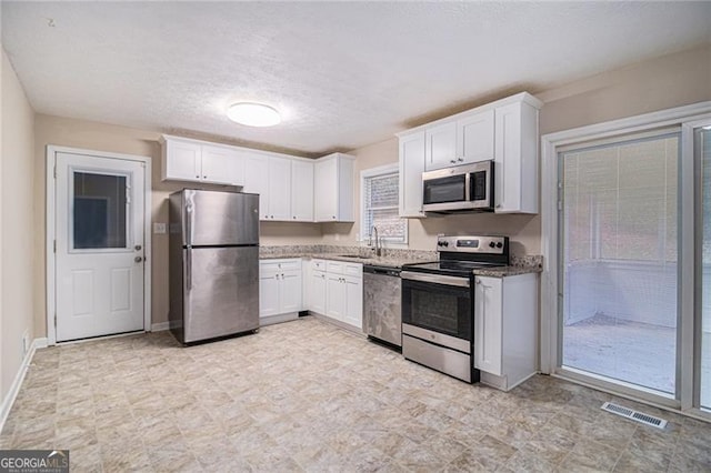 kitchen featuring white cabinetry, sink, a textured ceiling, and appliances with stainless steel finishes