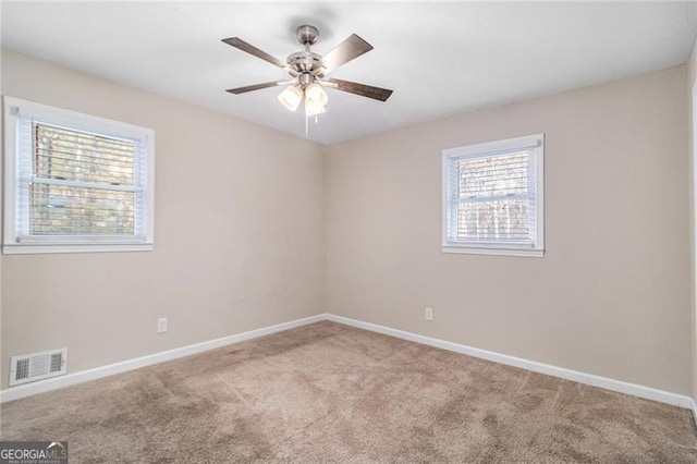 carpeted spare room with ceiling fan and plenty of natural light