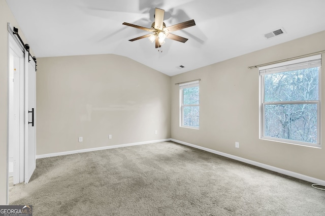 unfurnished room featuring a barn door, ceiling fan, carpet floors, and lofted ceiling