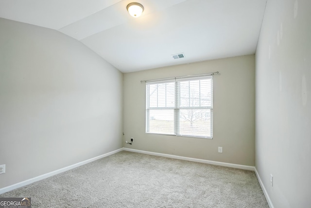 spare room featuring light colored carpet and vaulted ceiling