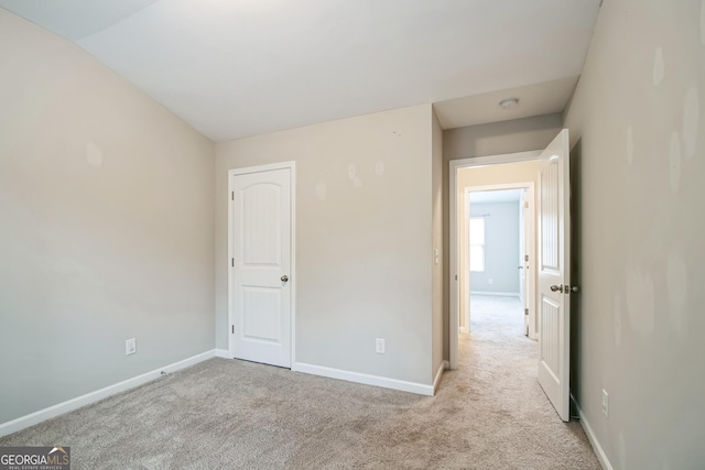 unfurnished bedroom with light carpet and lofted ceiling